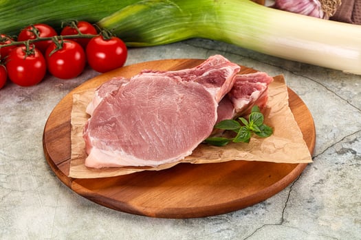 Raw pork on wooden board with vegetables photo