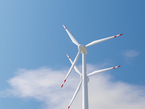 Low-angle view of a wind turbine with red-tipped blades in the sky. photo