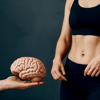 Symbolic image showing a fit woman in sportswear and a human brain held in a hand, illustrating the connection between mental focus and body transformation. Ideal for weight loss, neuroscience photo