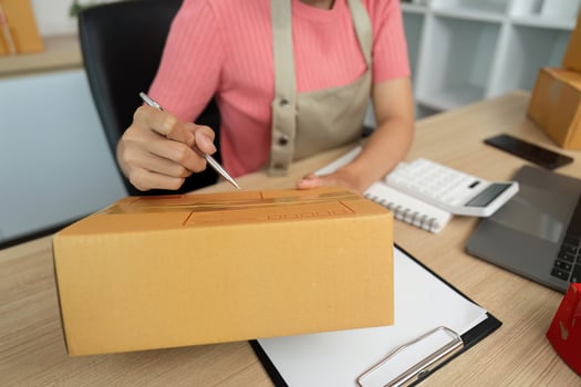 Small Business Operations. Woman Writing on Package for Shipping photo