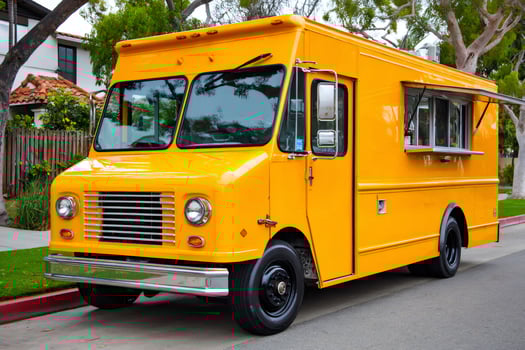 Bright yellow food truck parked on suburban street offering delicious meals photo