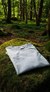 A white t - shirt sitting on a moss covered rock photo
