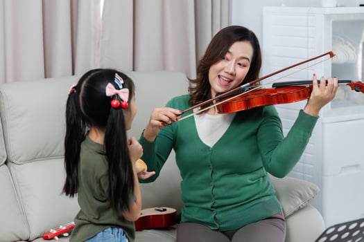 Musical Interaction. Mother and daughter enjoy playing violin together at home. photo