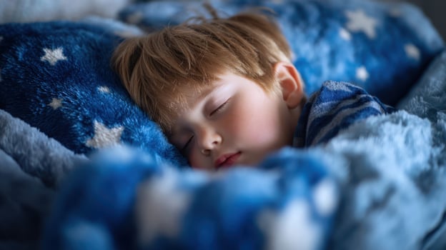 The peaceful sleeping boy wrapped in a cozy blue blanket with stars. photo