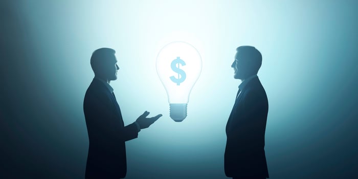 Businessmen discussing about a profitable idea symbolized by a light bulb and a dollar sign photo