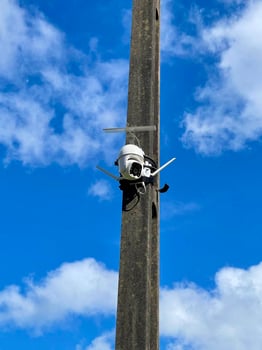 A camera mounted on a pole with a blue sky photo