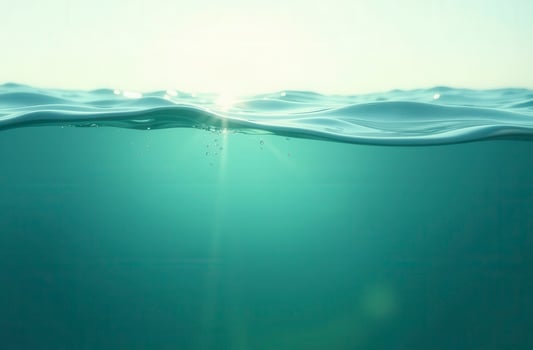 Sunlight entering deep clear ocean water with bubbles rising to surface photo