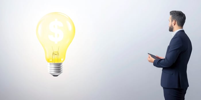 Businessman looking for a new money making idea looking at a lightbulb with a dollar symbol inside photo