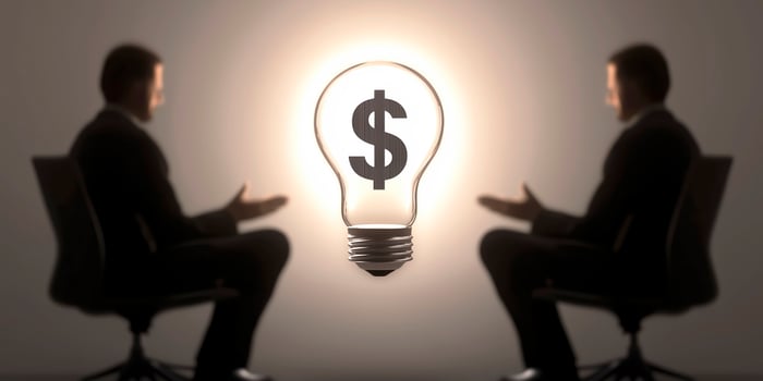 Businessmen discussing a profitable idea symbolized by light bulb and dollar sign photo