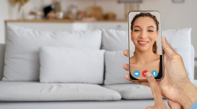A person is using a smartphone to connect in a call, showcasing a casual home environment. The individual on the screen appears happy and focused on the conversation. photo