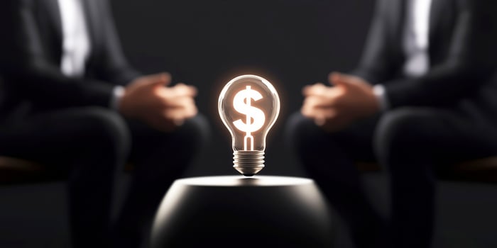 Businessmen discussing a bright idea for making money. Light bulb with dollar symbol glowing between two businessmen discussing new profitable ideas photo