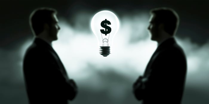 Businessmen considering light bulb with dollar sign inside symbolizing financial, representing profitable idea, investment or new business photo