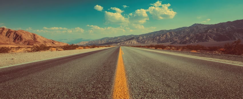 The endless road stretches through stunning desert landscapes under a bright blue sky. photo