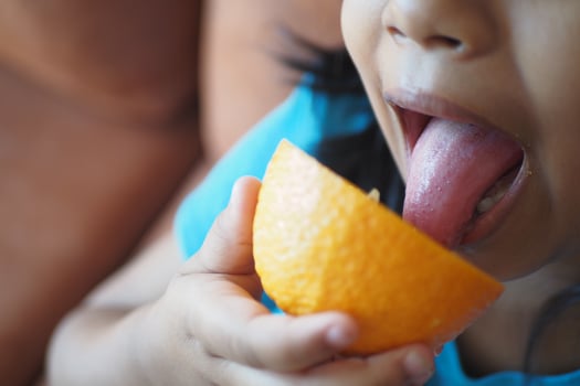 Child enjoying a slice of orange with delight photo