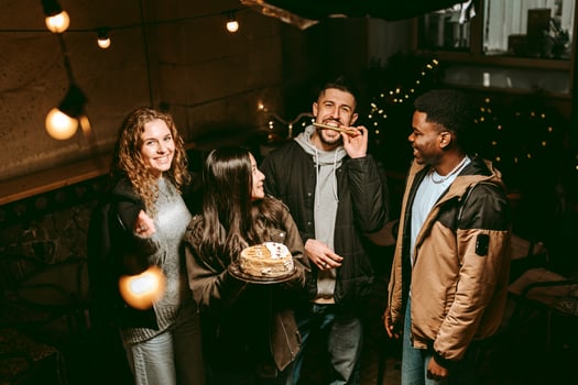Friends celebrating a birthday with cake and laughter during a cozy evening gathering photo