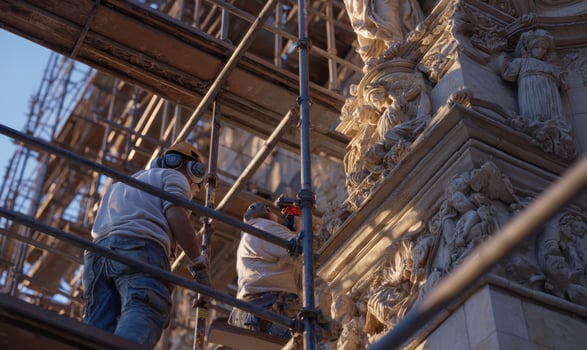 Workers Carefully Restoring Ornate Stone Facade Of Old Building Using Scaffolding System photo