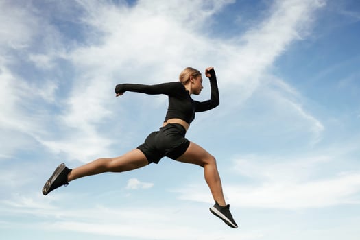 Jumping against the sky. Beautiful,, fitness, woman in sport clothes is outdoors photo