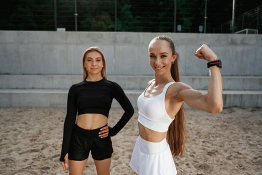 Showing,, biceps. Two sportive women are outdoors together photo