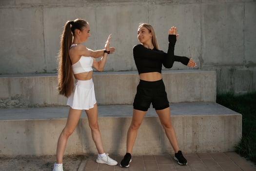 Front ,view, stretching, exercises. Two sportive women are outdoors together photo