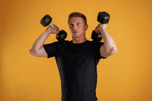 Lifting dumbbells. Man is against background in the studio photo