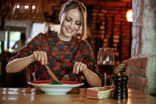 Uses, a fork and ,a knife. Woman is in the restaurant with food and drink photo