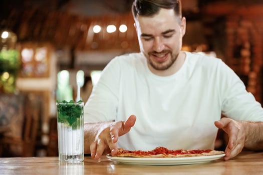 Man is sitting in ,the restaurant and eating a pizza photo