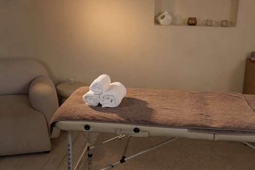 Minimalist spa interior with a clean massage table topped with neatly rolled white towels in a calming environment ready for a wellness treatment session. photo