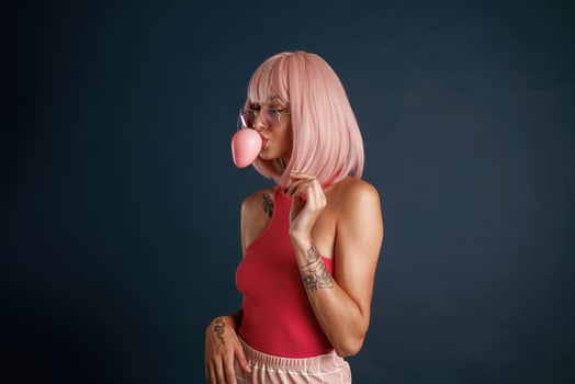 Blowing a gum bubble, pink hair. Beautiful young woman is against background photo