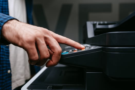 Person uses a multifunction printer to operate photocopying or scanning functions in an office setting during daylight hours photo