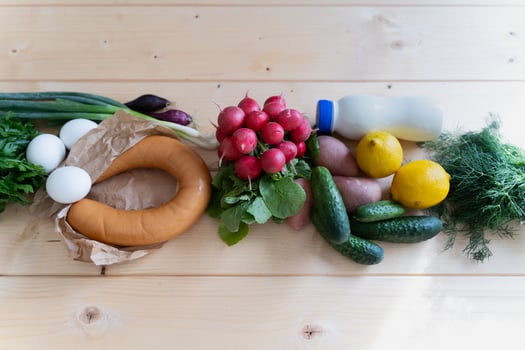 Traditional okroshka components, from chopped vegetables to herbs, styled on a rustic wooden table. photo