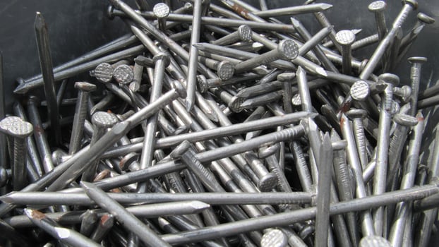 Metal nails scattered in a container, showcasing construction materials for various projects and repairs photo