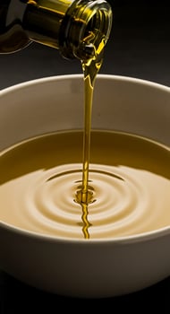 A bottle of olive oil being poured into a bowl photo