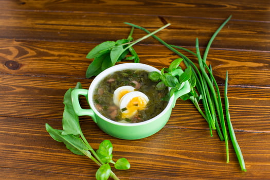 Ukrainian dish borscht with greens and egg on a dark wooden table photo
