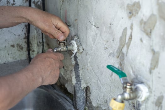 man repairs a faucet by tightening it on an old wall with a wrench photo