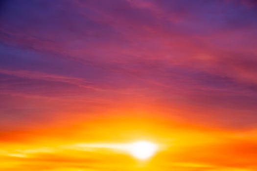 A vibrant sunset paints the sky in vibrant shades of orange, yellow and purple as the sun dips below the horizon photo