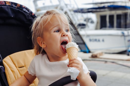Toddler blonde girl enjoying ice cream at a marina during summer travel trip photo