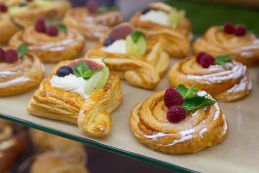 Delicious baking with berries and custard cream in glass showcase. Food photo