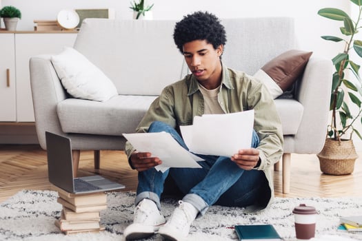 Home education concept. Black teen student making educational project for his online college course indoors. African American guy with papers preparing for web conference or remote test photo