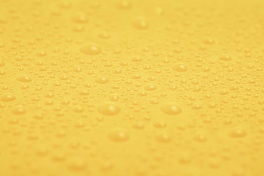 Texture of water drops on yellow plastic. photo