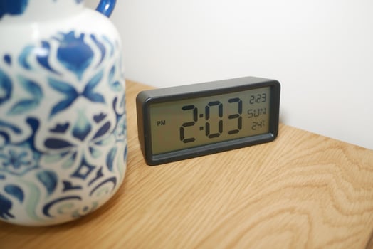 Clock on wooden table next to decorative ceramic jug photo