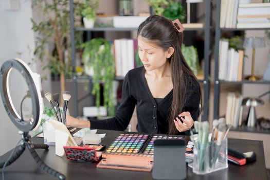 Asian woman beauty influencer makeup artist vlogger live streaming makeup tutorial on smartphone for social media. photo