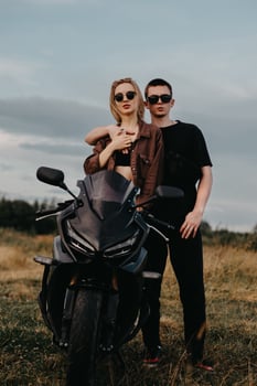 A young beautiful couple, hugging, are standing near a sports motorcycle photo