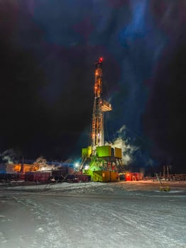 illuminated oil drilling rig working at night in snowy environment. Mining. Mobile photo