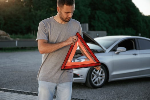 Holding red sign, broken, automobile... Man is with his car outdoors.. photo