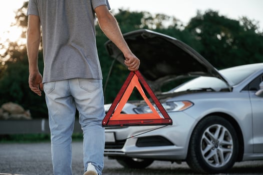 Holding ,,,red sign, broken automobile. Man is with his car outdoors.. photo