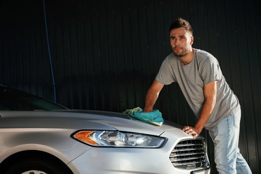View from the side, using ,cloth, to ,polish the automobile. Man is with his car outdoors photo