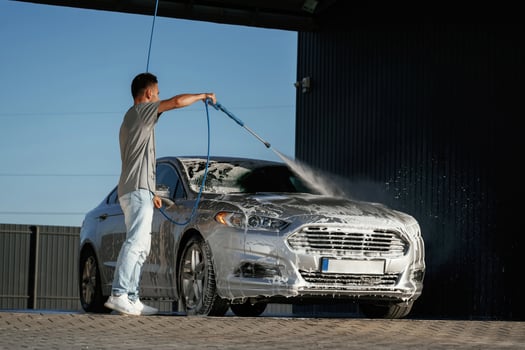 High ,pressure washer, soap and foam. Man is with his car outdoors photo