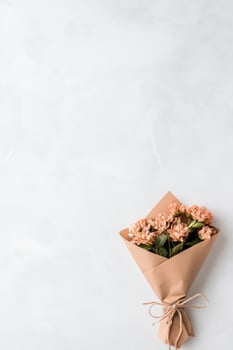 Small Peach Blossoms Wrapped in Brown Paper, Tied with Jute Rope on Light Background, Suggests Gardening or Decorative Floral Arrangement photo