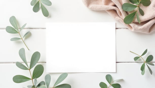 Blank paper with eucalyptus leaves on white wooden table top view photo