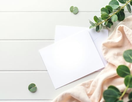 Blank white envelope with eucalyptus leaves on white wooden background photo